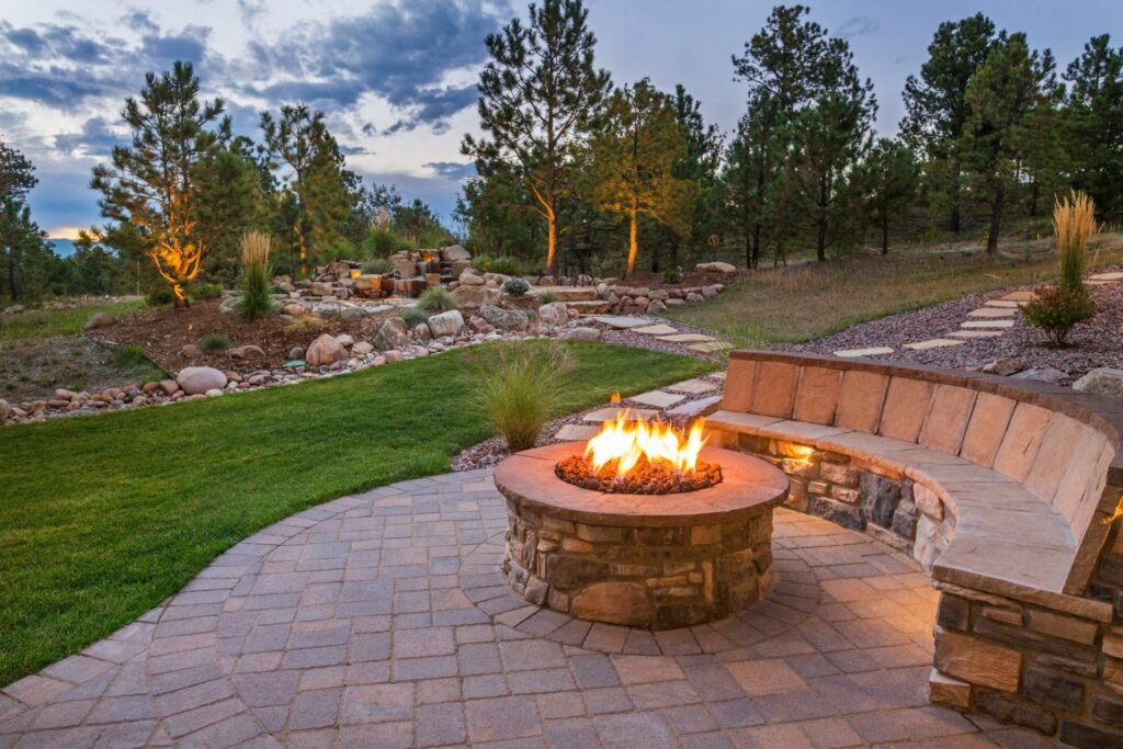 Custom stone fire pit and paver patio with built-in seating area at a Brookfield, CT backyard