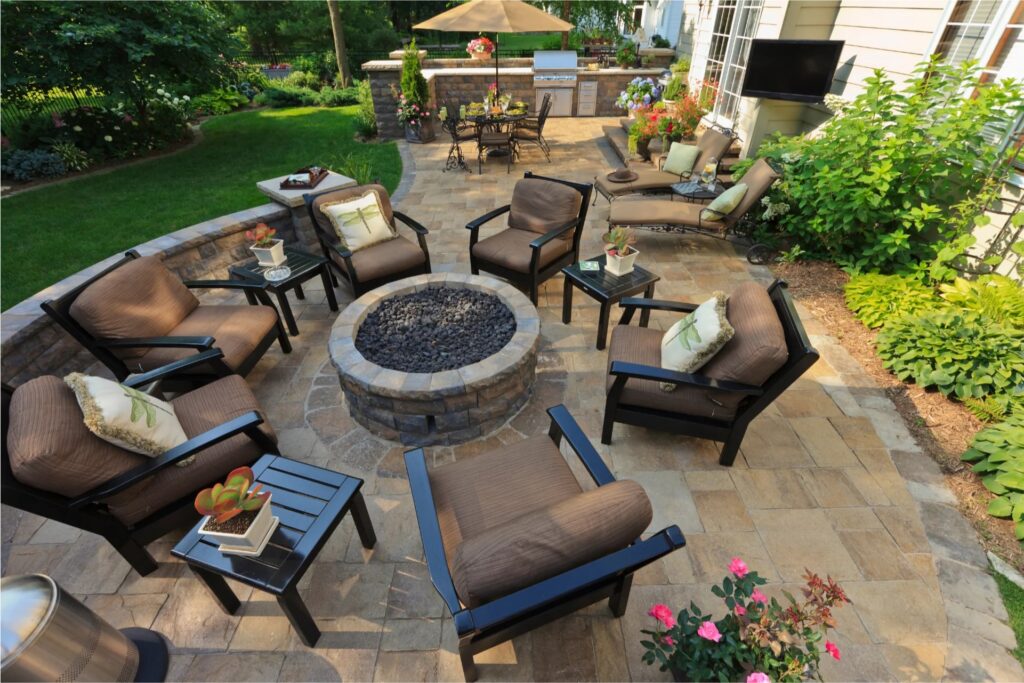 Custom outdoor living patio with fire pit seating area, outdoor kitchen, and professional landscaping in Connecticut