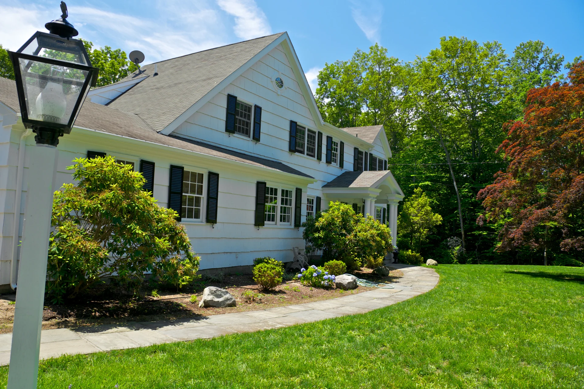 Well-maintained residential landscape with foundation plantings, shrubs, and lawn at a home in Newtown, CT